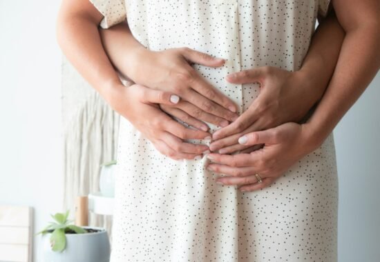 Two hands over a woman's belly